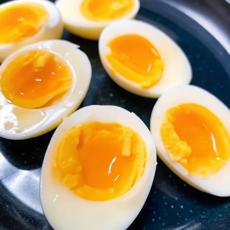 Close-up of perfectly cooked jammy eggs with a creamy, golden yolk, sliced in half and served on a wooden board.