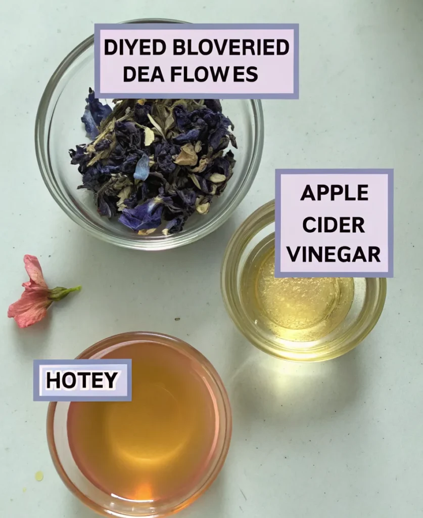 A clear glass cup filled with vibrant blue butterfly pea flower tea and floating edible flowers.