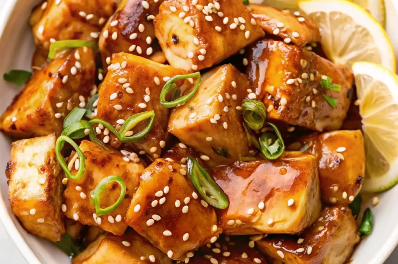Glazed Salmon Bites garnished with sesame seeds and green onions, served with lemon slices—an easy but delicious dinner and a good fish dish.