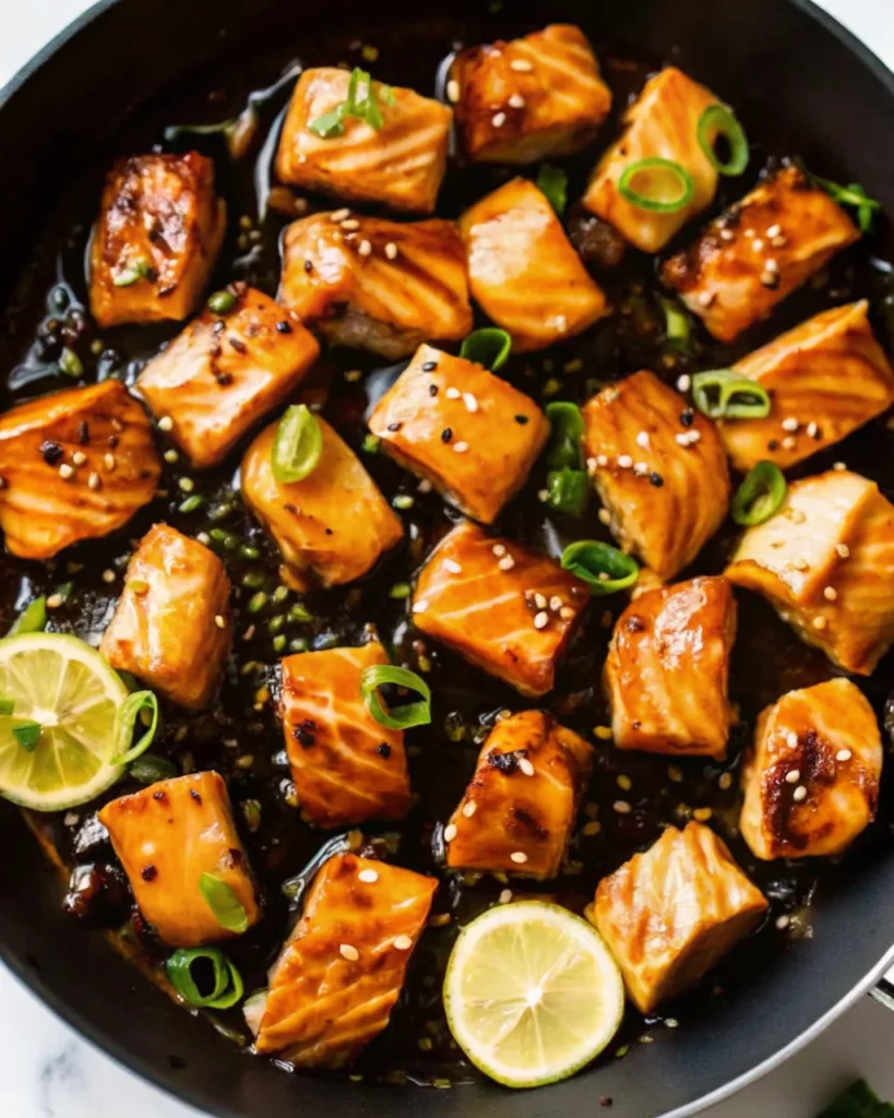 Glazed Salmon Bites garnished with sesame seeds and green onions, served with lemon slices—an easy but delicious dinner and a good fish dish.