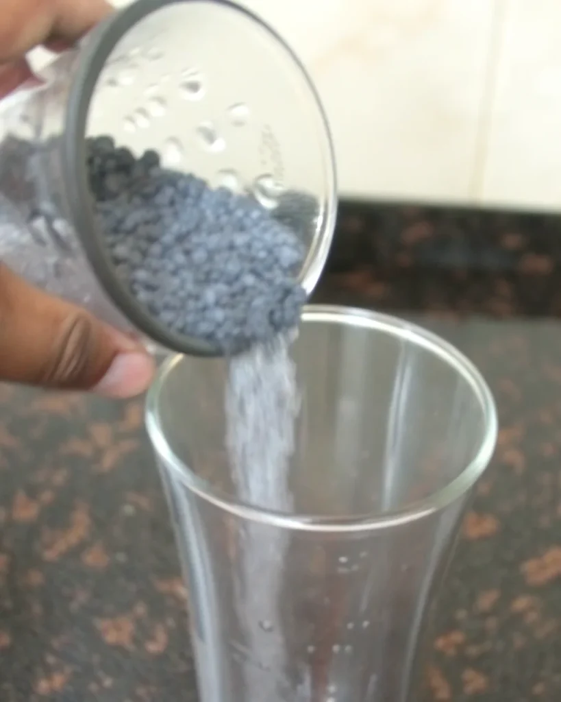 Refreshing basil seed drink in clear glass with soaked sabja seeds and fresh basil leaves on wooden surface