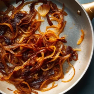 Caramelized onions in a golden pan, showcasing rich, deep brown color and glossy texture—perfectly cooked using the slow caramelization method.