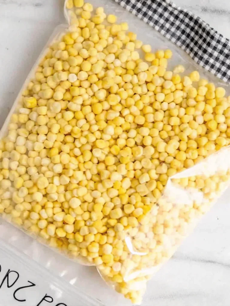 Three ears of sweet corn on the cob, blanched and packed in a labeled freezer bag, ready for freezing.