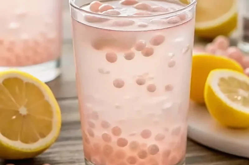 Glass of Japanese pink salt diet drink with lemon and pink salt pearls, refreshing detox beverage for hydration and wellness.