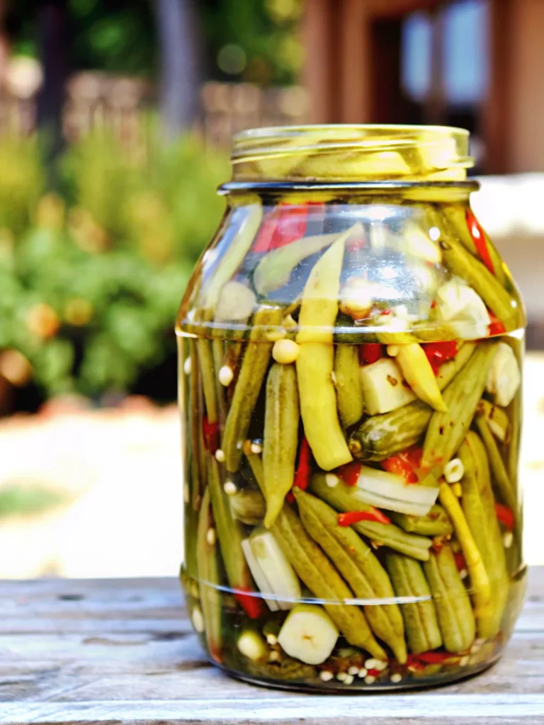 Homemade pickled okra recipe in glass jar with spices and garlic cloves