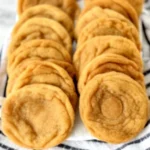 Golden pumpkin snickerdoodle cookies shaped into crispy cones arranged on striped kitchen towel, showcasing fall spiced cookie technique