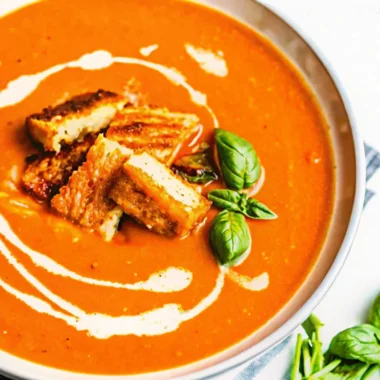 Roasted tomato soup with fresh tomatoes, creamy swirl, and crispy grilled cheese croutons topped with fresh basil.