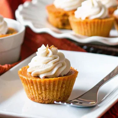 Keto pumpkin recipe mini pies with almond flour crust and sugar-free whipped cream on white plate