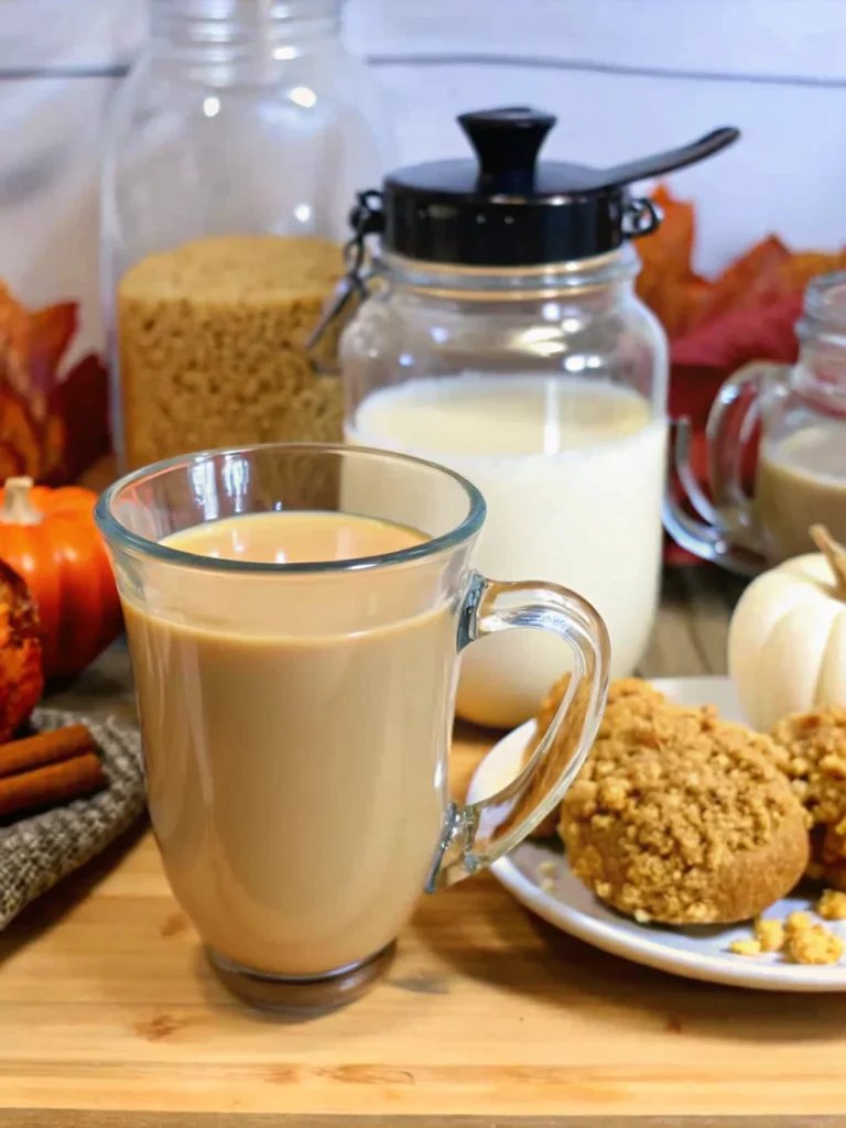 Homemade pumpkin creamer being poured into a white coffee mug with steam rising, showing the rich orange color and creamy texture of the fall-spiced coffee additive