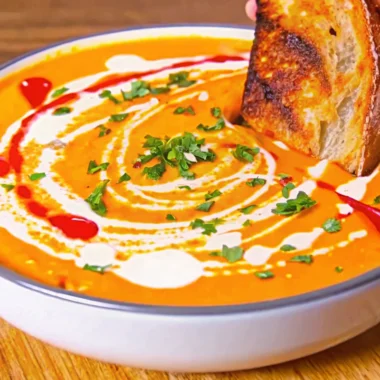 Creamy roasted butternut squash soup garnished with fresh cilantro and coconut milk swirl in white bowl