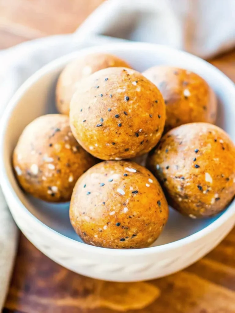 No-bake pumpkin energy balls on parchment paper with fall spices and ingredients, healthy pumpkin pie flavored snacks
