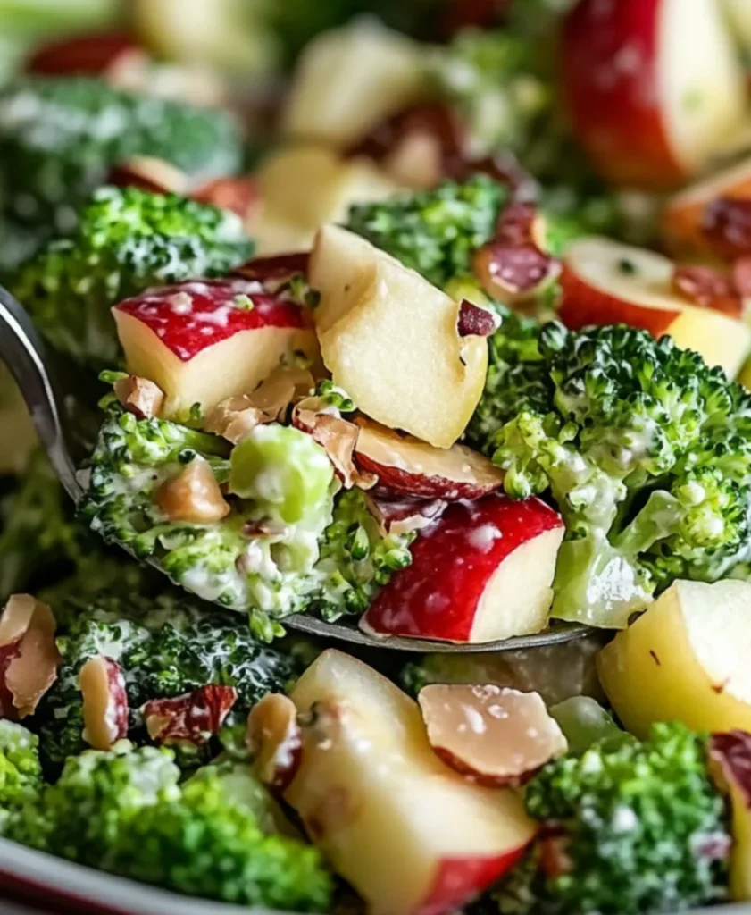 Fresh Honeycrisp apple salad with broccoli florets, cranberries, and nuts in white serving bowl, featuring vibrant colors and creamy honey dressing