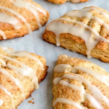 Golden pumpkin scones recipe with warm spices arranged on parchment paper, showing flaky texture and perfect triangle shape