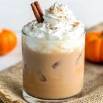 A cozy mug of Pumpkin Spice Chai Latte topped with whipped cream and a sprinkle of pumpkin pie spice, perfect for fall
