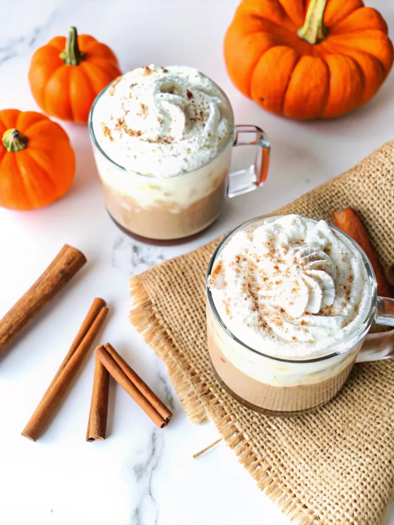 A cozy mug of Pumpkin Spice Chai Latte topped with whipped cream and a sprinkle of pumpkin pie spice, perfect for fall