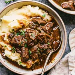 Tender Instant Pot beef tips in rich brown gravy served over mashed potatoes - easy instapot recipe for comfort food dinner