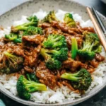 Chinese beef and broccoli stir fry in black skillet with glossy brown sauce, tender beef strips and bright green broccoli florets