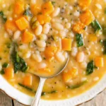 Creamy white bean soup with cannellini beans, vegetables, and fresh herbs served in a rustic bowl with crusty bread