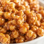 Golden brown Amish caramel corn with almonds spread on parchment paper, showing perfectly coated kernels with glossy caramel finish