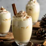 Creamy homemade eggnog recipe topped with fresh nutmeg and a cinnamon stick in a festive glass.
